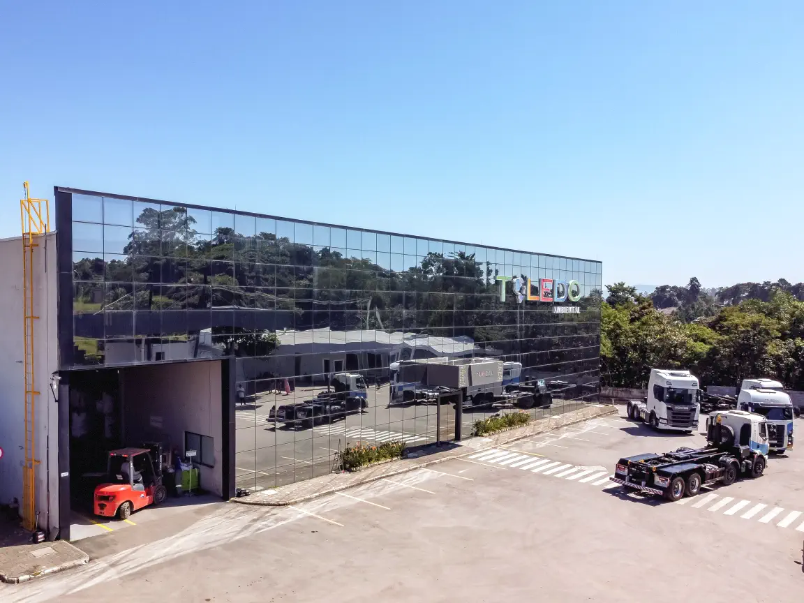 Fachada espelhada da matriz da Toledo Ambiental com frota de caminhões